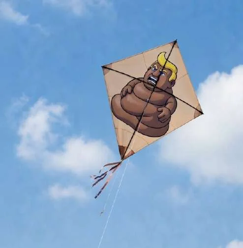 Kite shaped like turd-Trump flying in a blue sky
